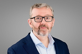 Steve Mason (CRO von Bender) Älterer Mann mit Brille, grauen Haaren und Bart mit weißem Hemd und dunklem Sakko